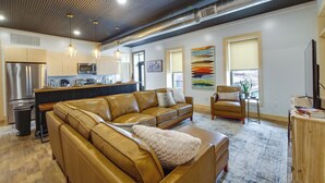 A modern living room with a leather sofa, a wooden coffee table, and a TV stand. - Downtown Millersburg Retreat w/ Sleek Interior! (Millersburg)