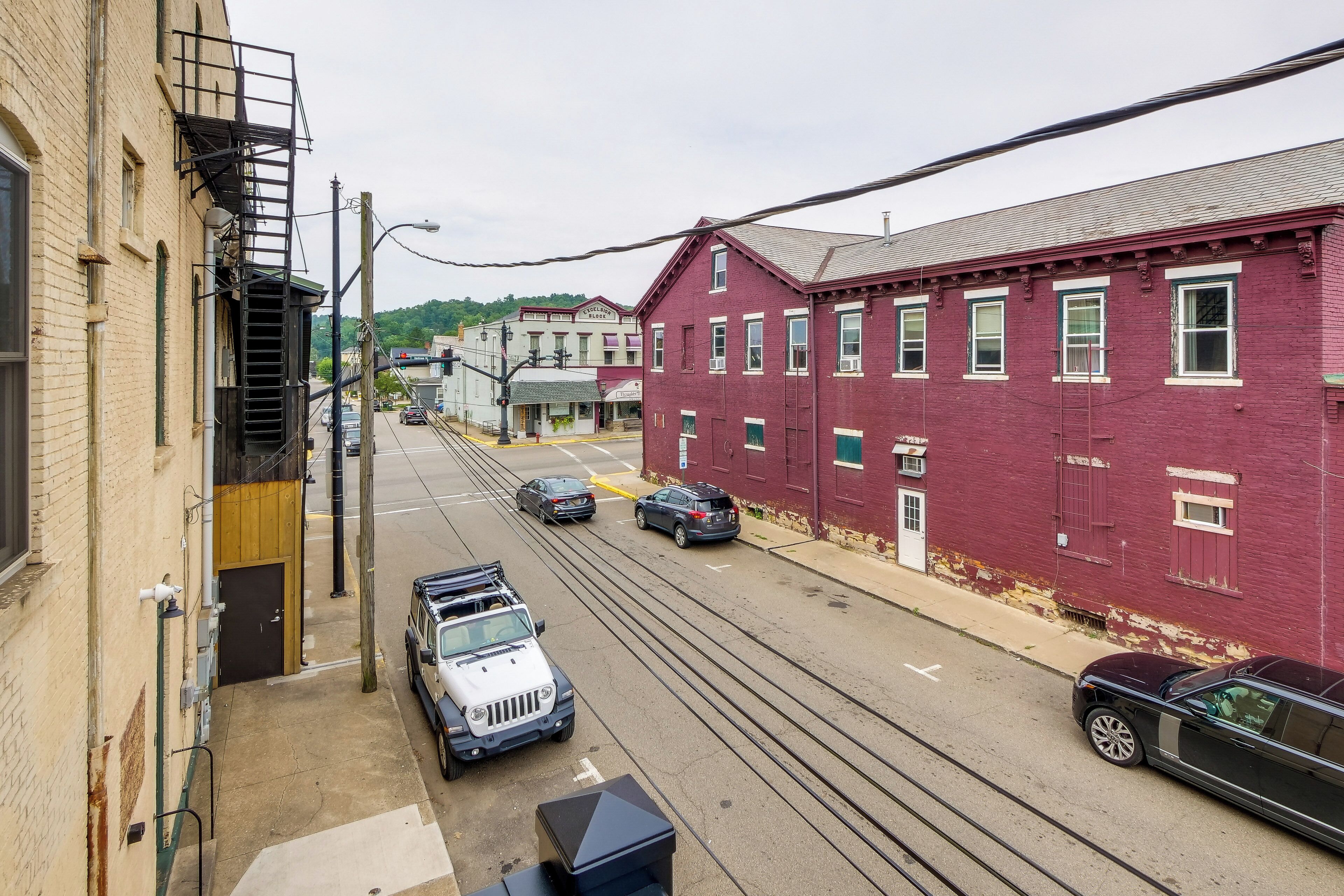 A street view with a red building, a white car, and a black car parked on the side.