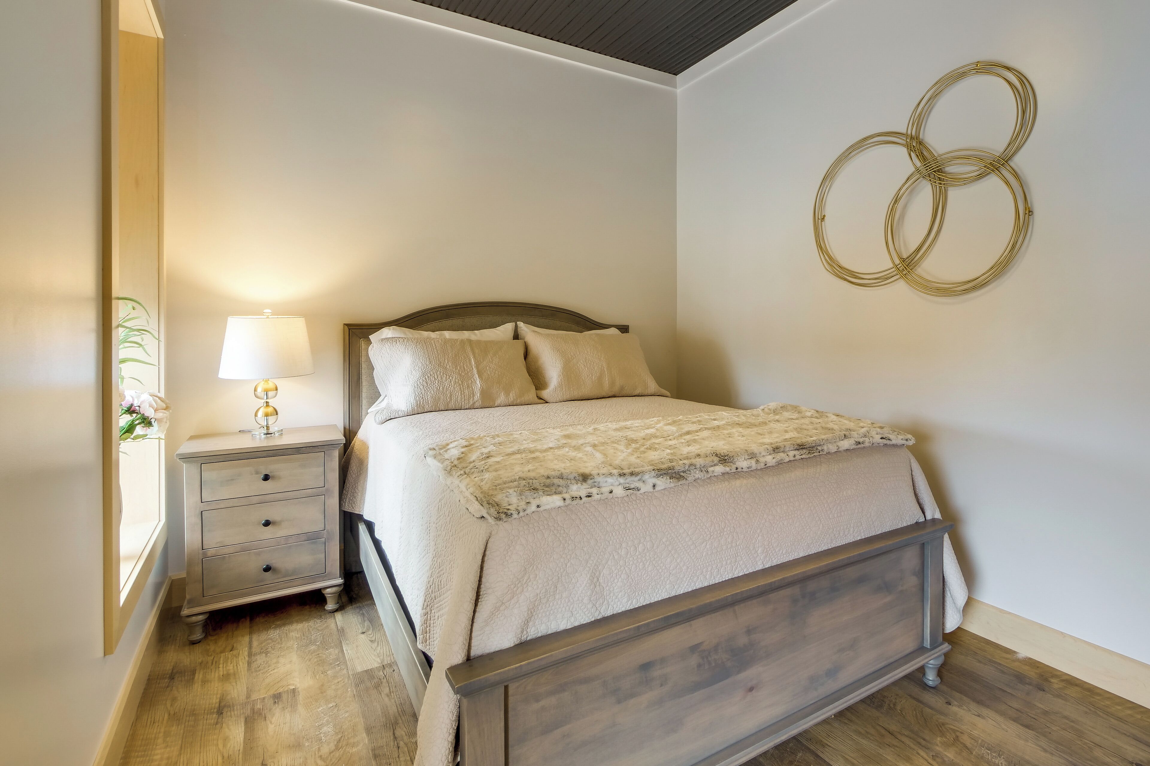 A bedroom with a wooden bed, a nightstand with a lamp, and a wall-mounted circular decoration.