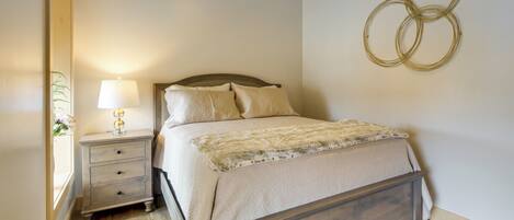 A bedroom with a wooden bed, a nightstand with a lamp, and a wall-mounted circular decoration.