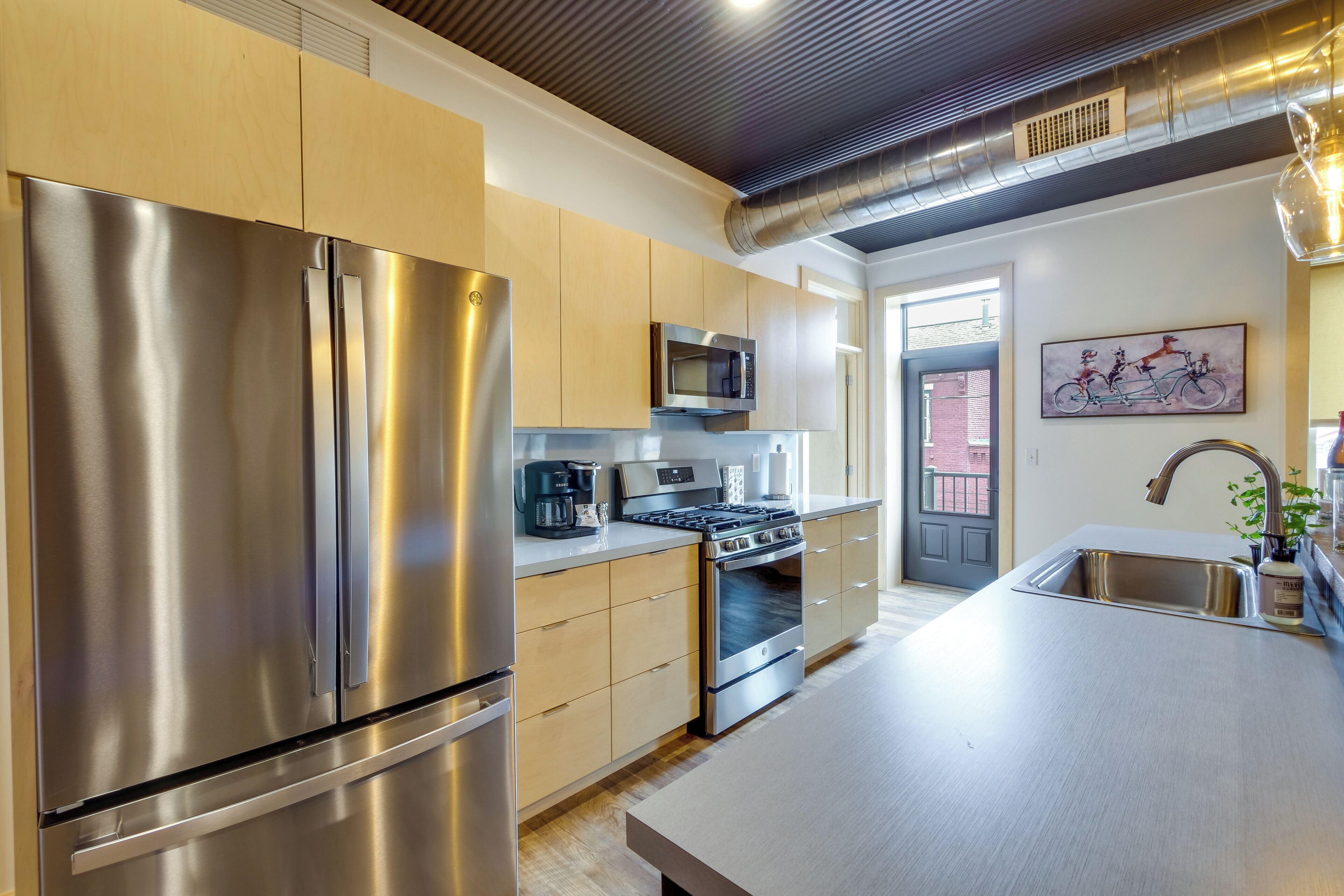 A modern kitchen with stainless steel appliances, wooden cabinets, and a large island with a sink.