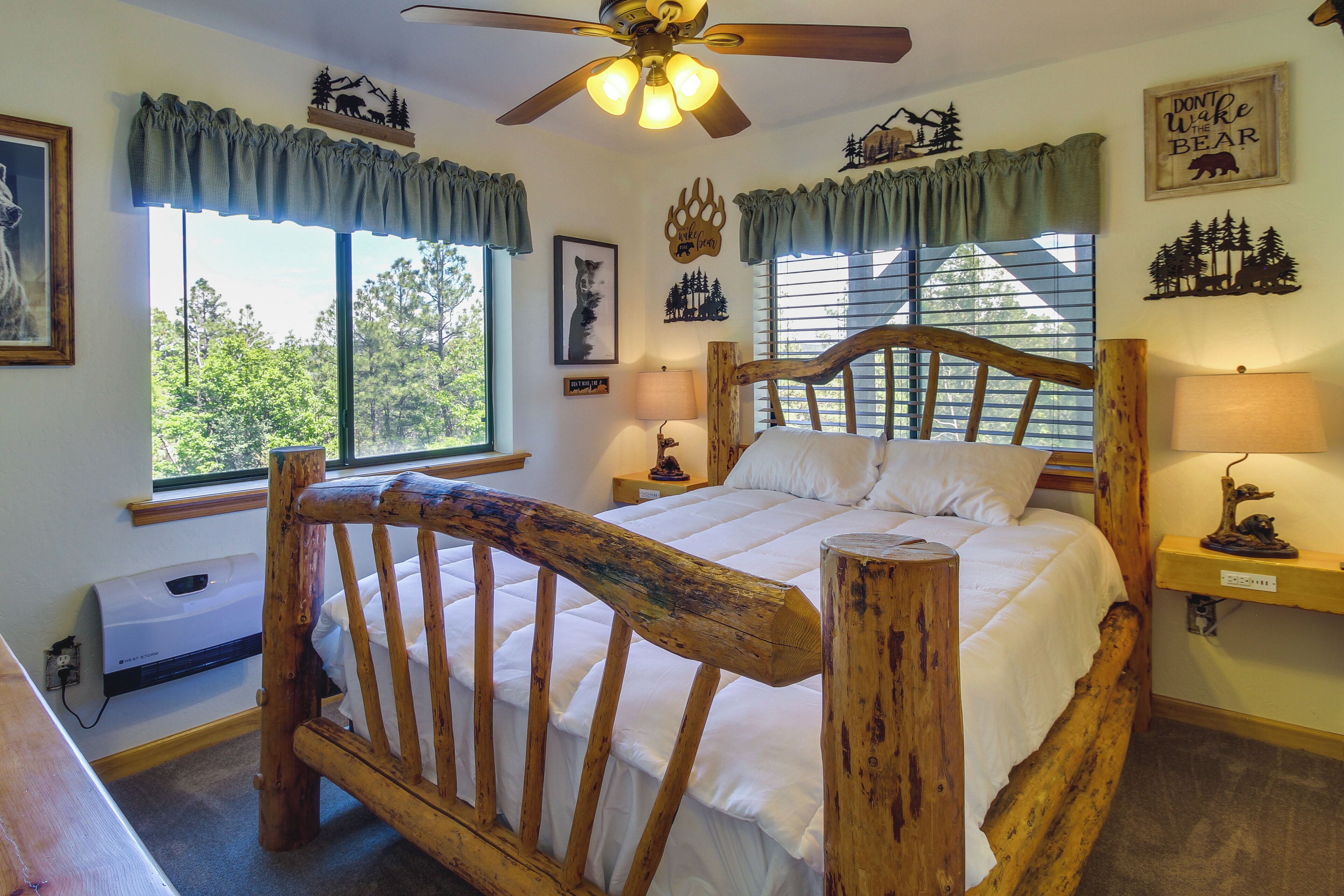 A wooden bed with a headboard, a ceiling fan, and a window with curtains.