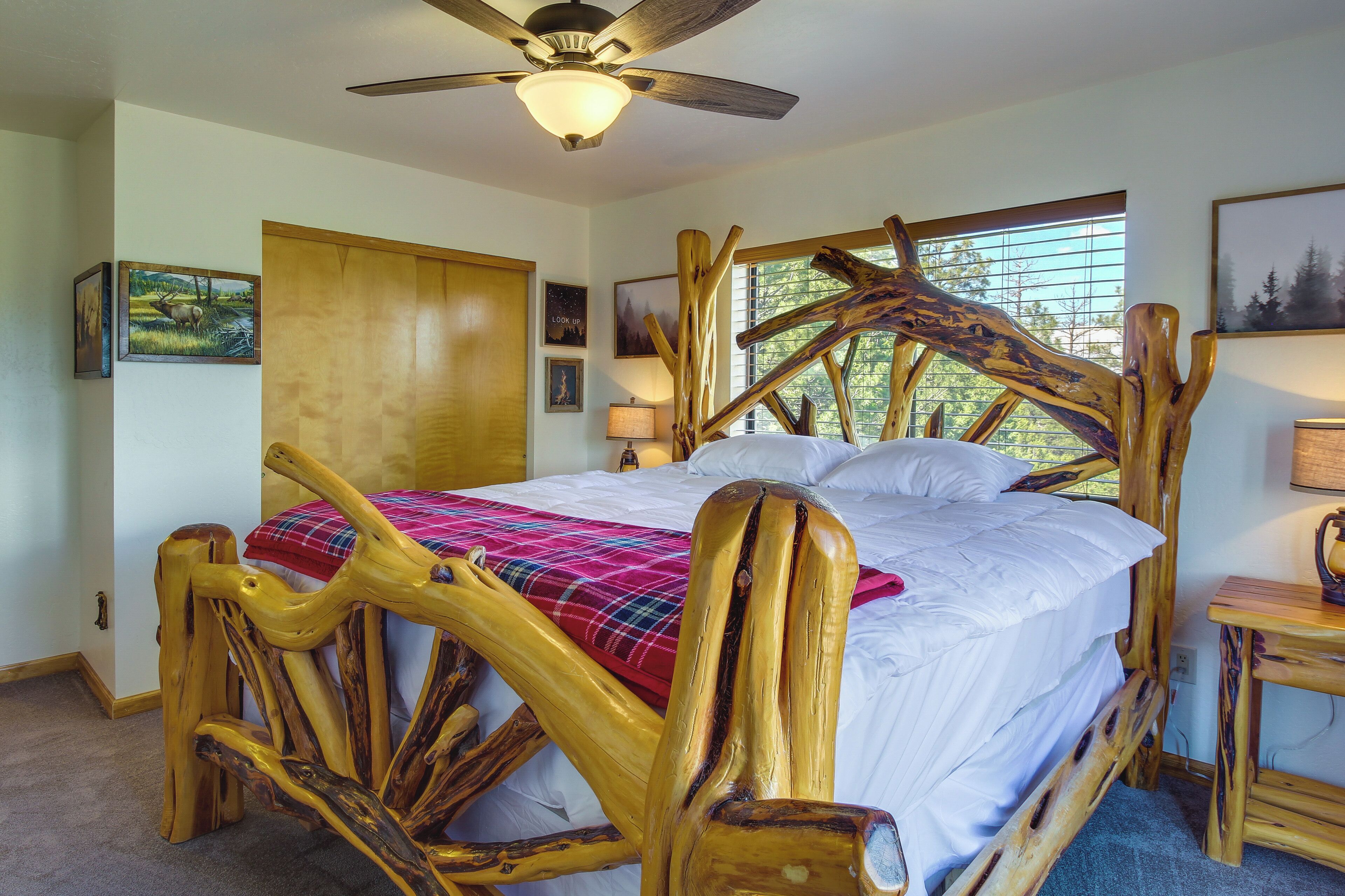 Ein Bett mit Holzrahmen und einem einzigartigen Design, ein Deckenventilator und ein Fenster mit Jalousien.