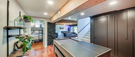 A pool table in a room with wooden flooring, a staircase, and a dark-colored cabinet.