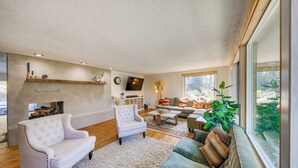 Un salon spacieux doté d’une cheminée, de sièges confortables et d’une grande fenêtre offrant une vue sur l’extérieur.