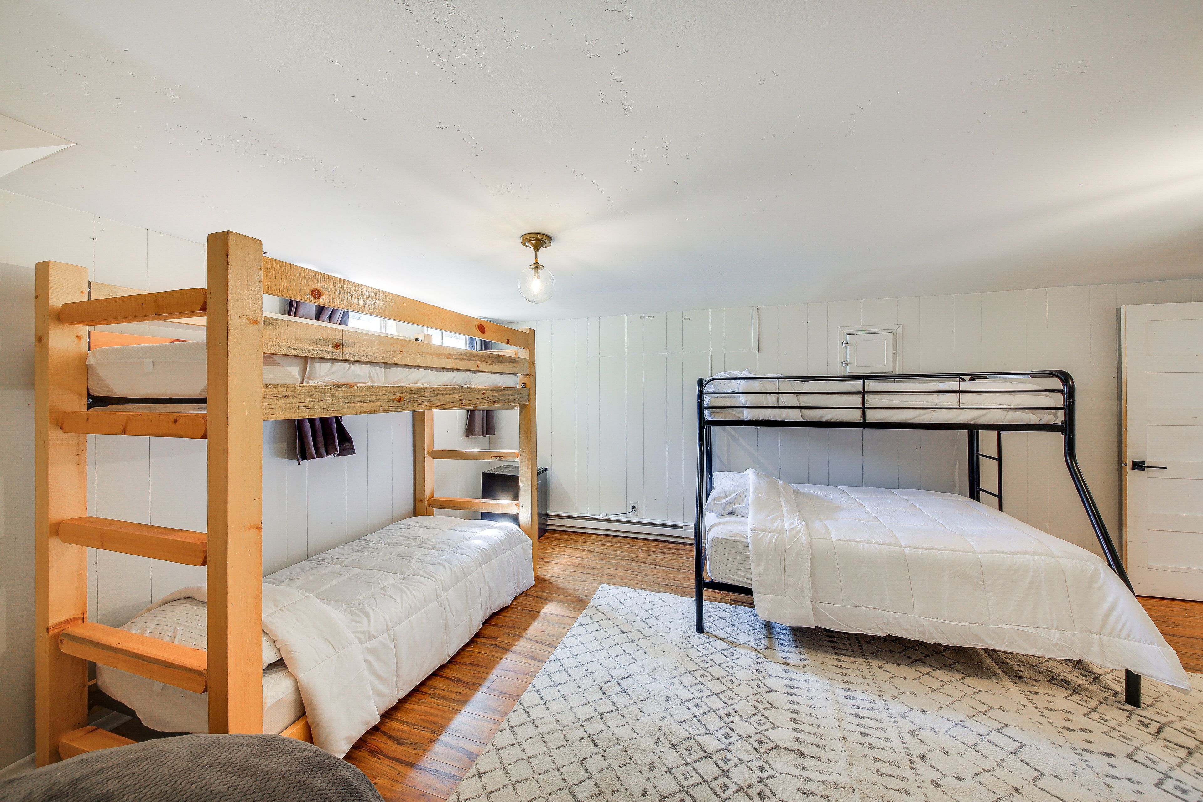 Une chambre de dortoir avec deux lits superposés, une étagère en bois et un tapis à motifs.