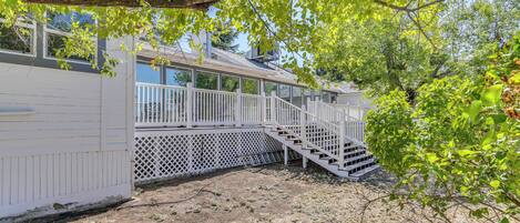 A covered outdoor area with a white fence, a staircase, and a view of a house in the background.