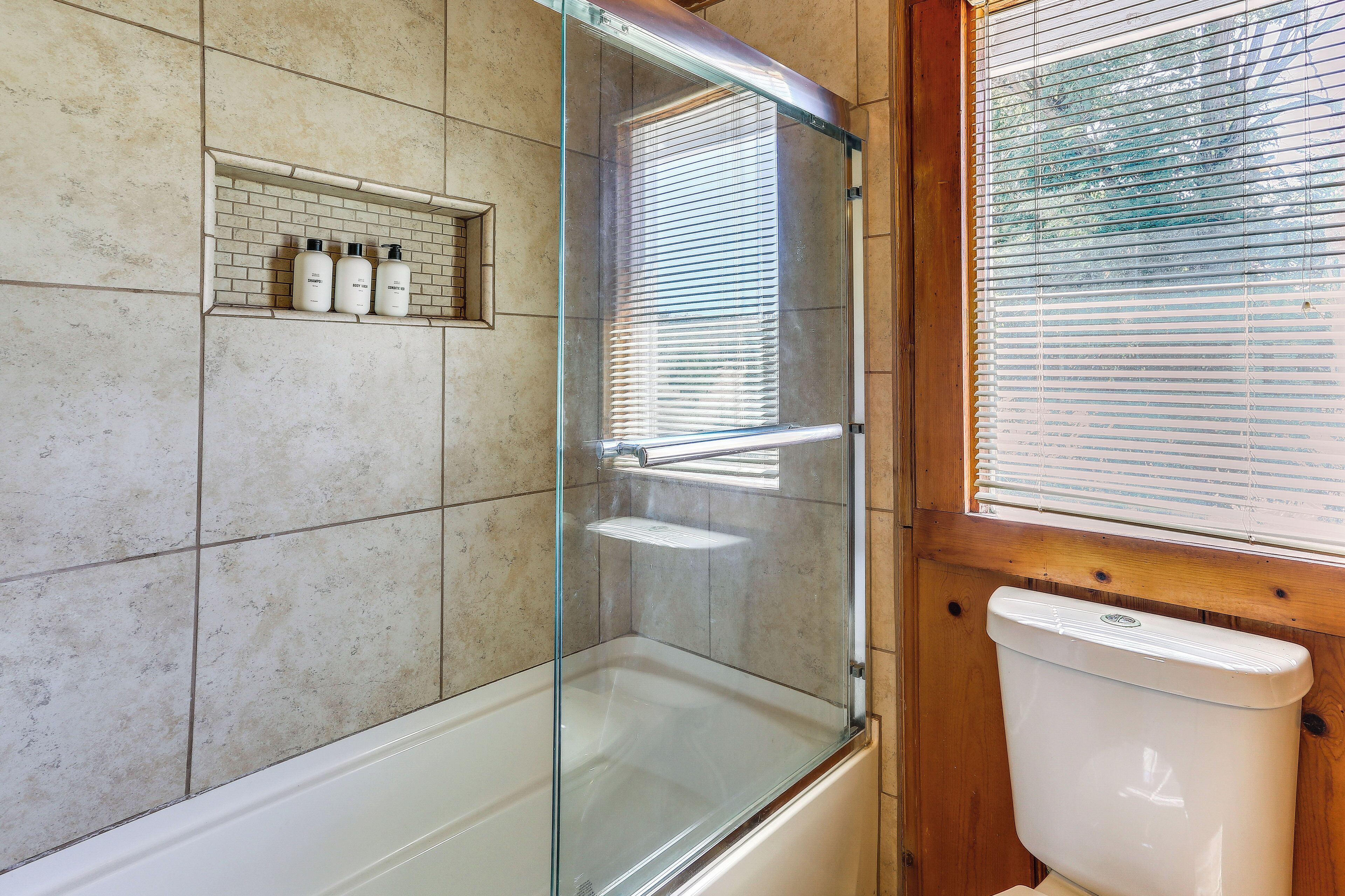 Une salle de bain avec une douche à parois de verre, un meuble-lavabo en bois et des toilettes.