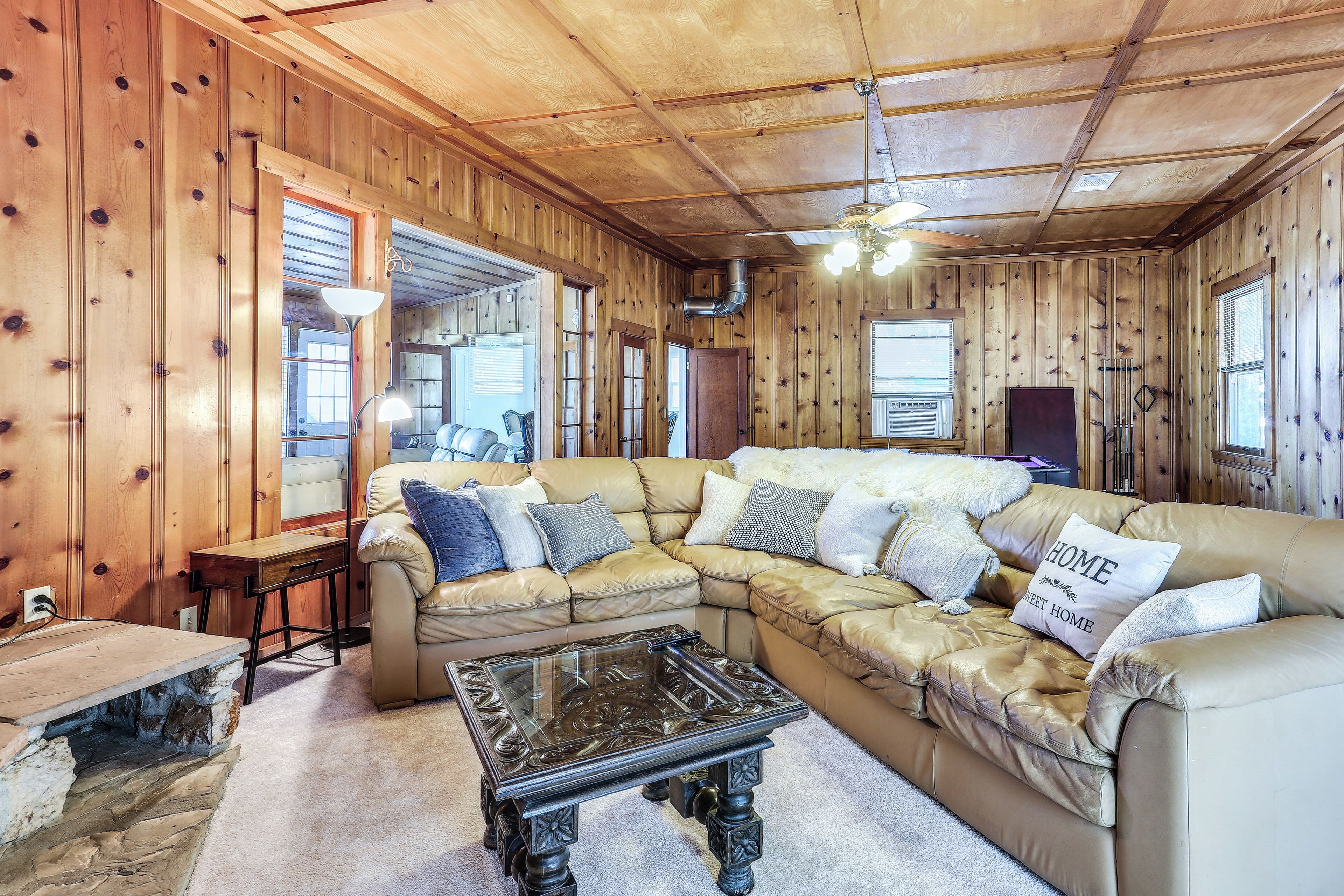 A cozy living room with a sectional sofa, a glass coffee table, and wooden walls.