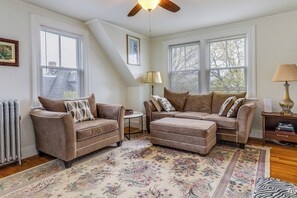 A living room with two sofas, a patterned rug, and a ceiling fan.