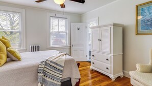 Une chambre à coucher avec un lit, une commode, une chaise et un ventilateur de plafond.