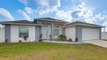 A two-story house with a garage, a front porch, and a well-maintained lawn.