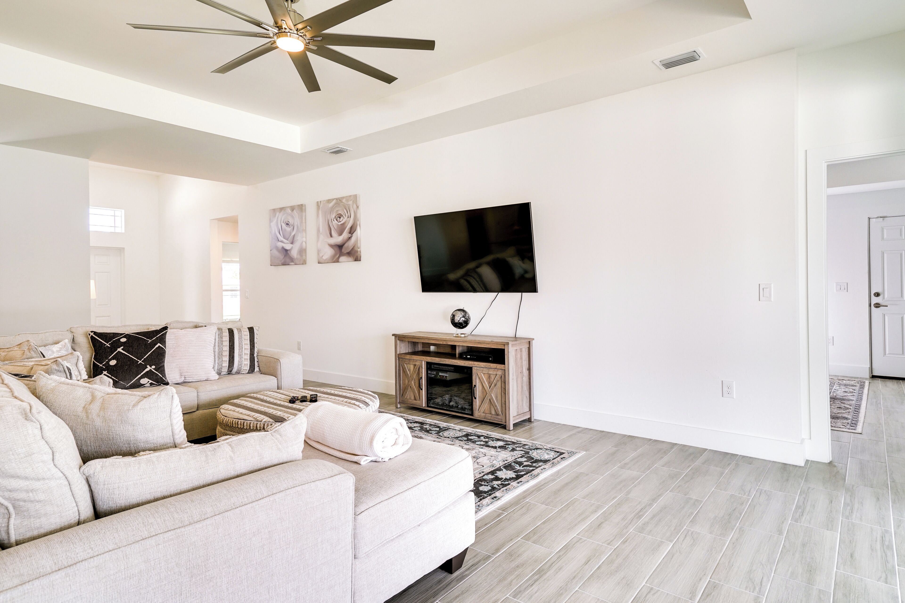 Una sala de estar moderna con un sofá color beige, un televisor de pantalla plana y un mueble de entretenimiento de madera.