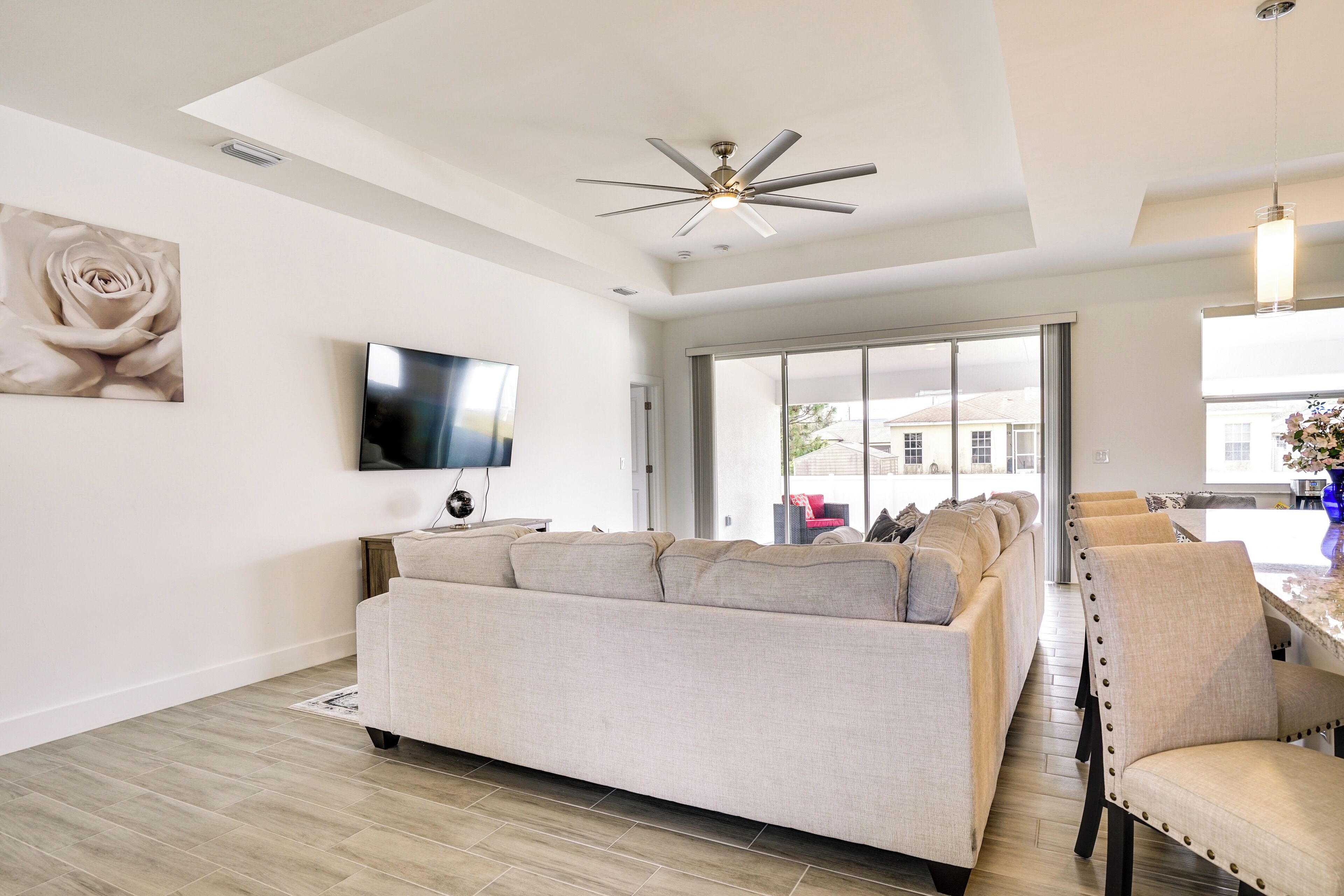 Una sala de estar moderna con un sofá grande color beige, un televisor de pantalla plana y un ventilador de techo.