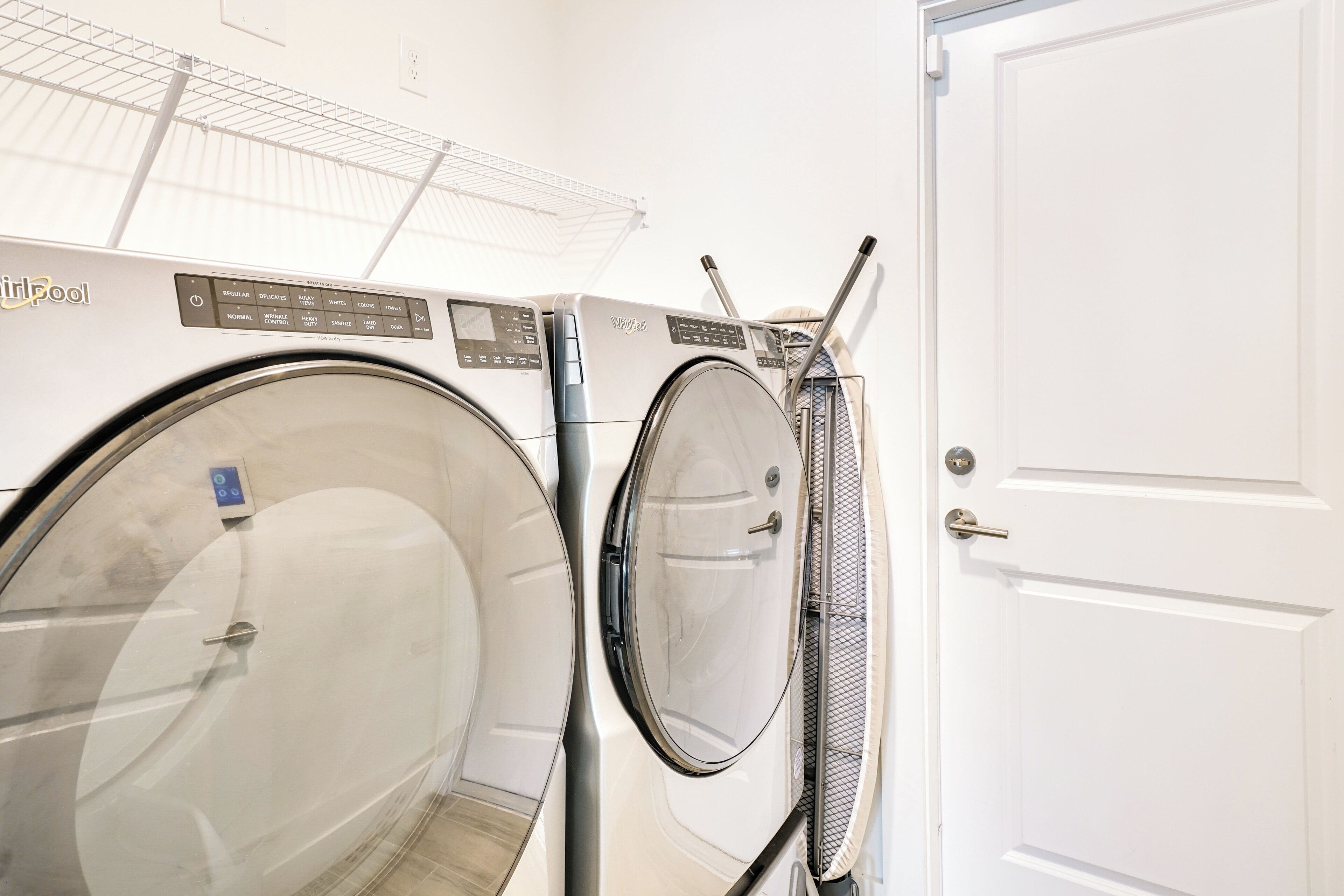 A laundry room with two front-loading washing machines and a white door.