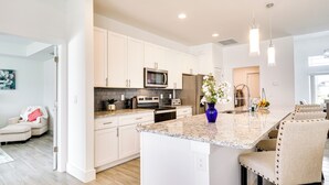 A modern kitchen with white cabinets, a granite countertop, and stainless steel appliances. - Furnished Lanai & Yard: Comfy Lehigh Acres Getaway (Lehigh Acres)