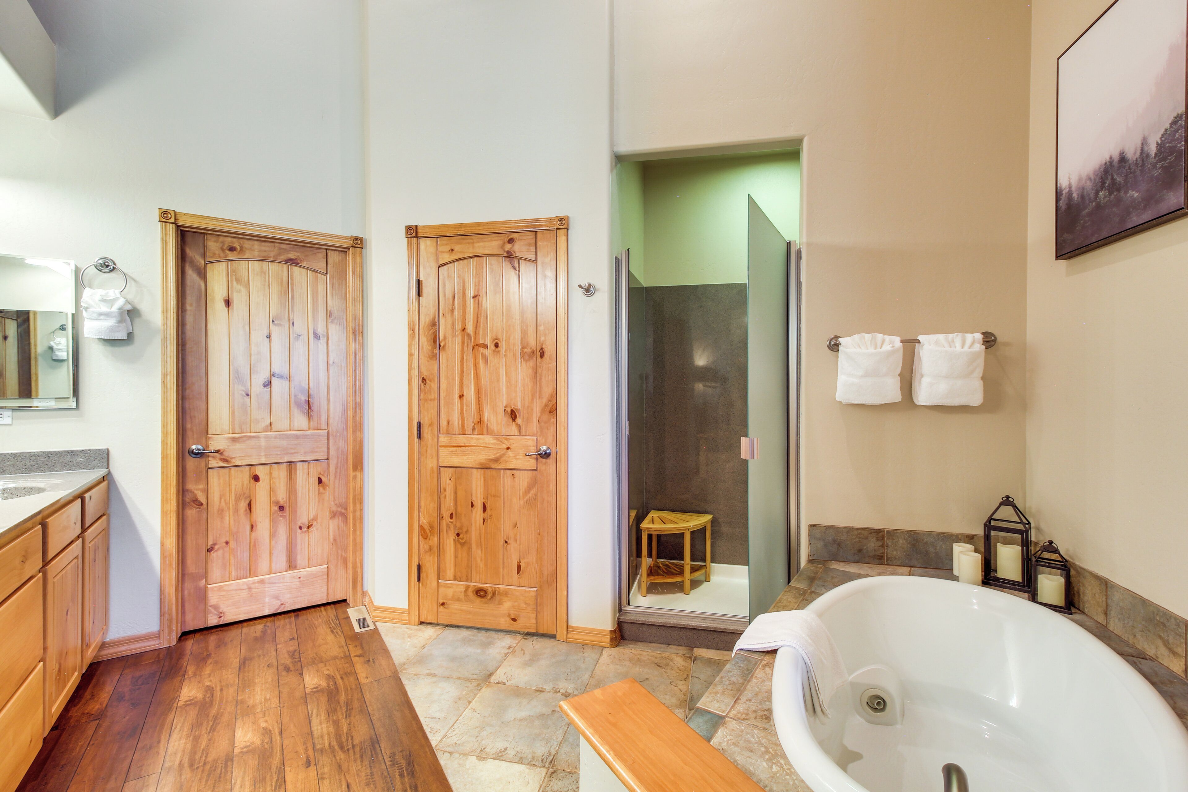 Une salle de bain avec une porte en bois, une douche, une baignoire et un banc.