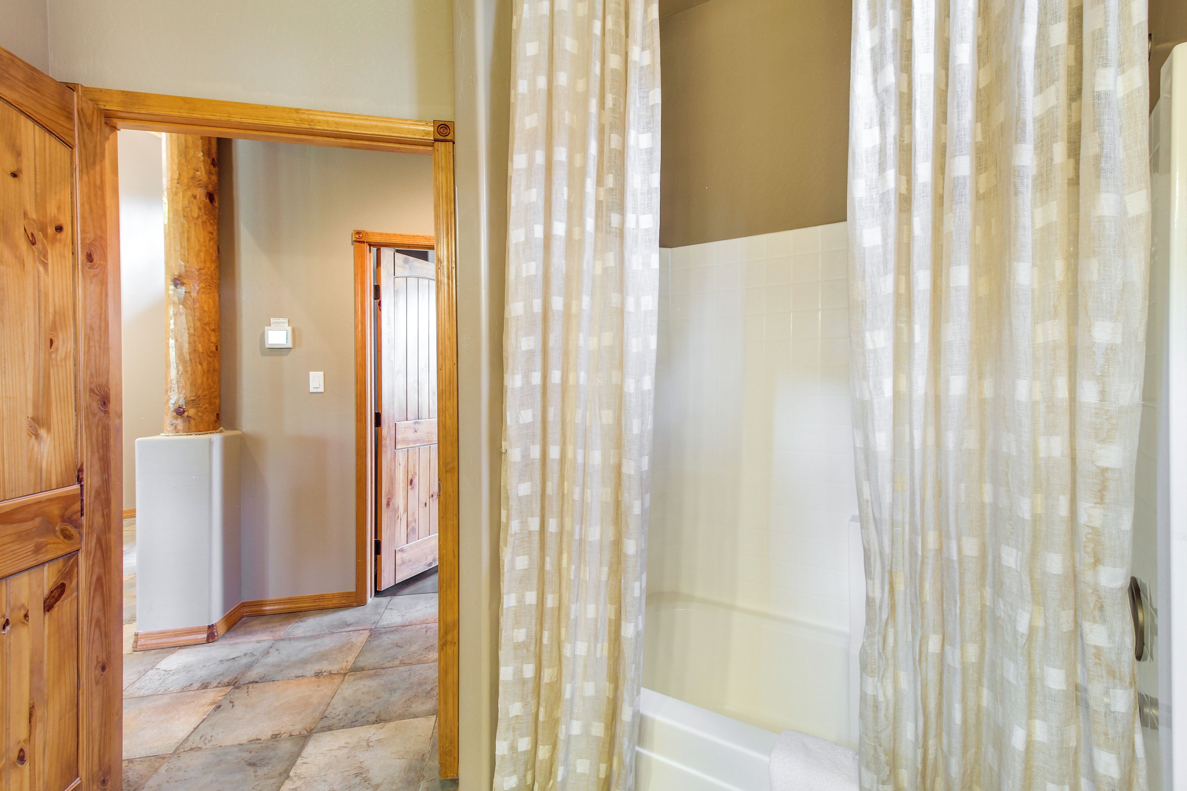 A hallway with wooden flooring, a white refrigerator, and a bathroom with a shower curtain.