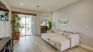 A modern living room with a sofa, a dining area, and a large window. - Sunny Fort Myers Home w/ Heated Pool! (Fort Myers)