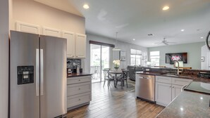 A modern kitchen with stainless steel appliances, a dining area with a table and chairs, and a large window providing natural light. - Sunny Fort Myers Home w/ Heated Pool! (Fort Myers)