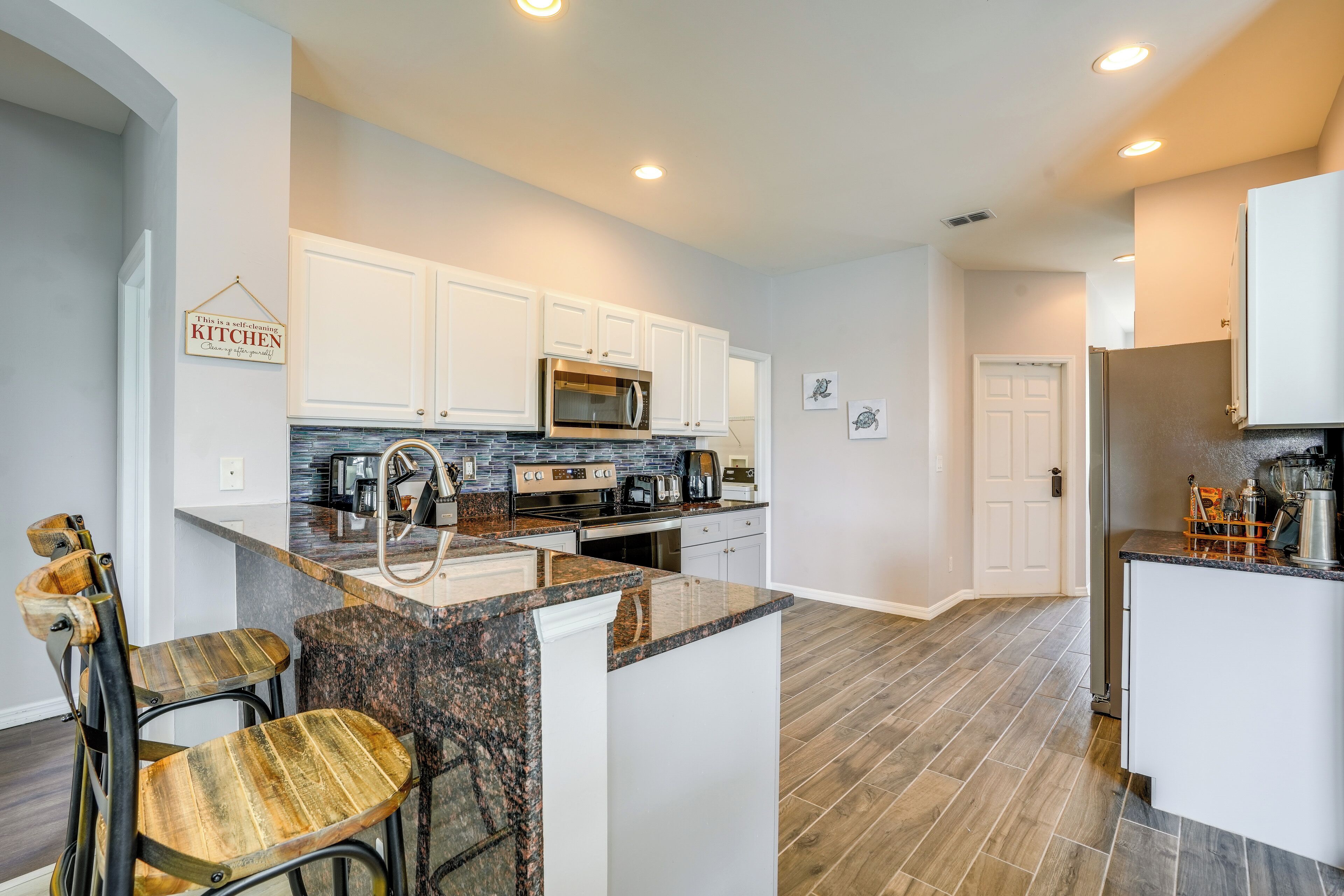 A modern kitchen with white cabinets, granite countertops, and a central island with bar stools.