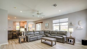 A modern living room with a sectional sofa, a coffee table, and a dining area with bar stools. - Sunny Fort Myers Home w/ Heated Pool! (Fort Myers)