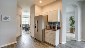 A modern kitchen with a large refrigerator, white cabinets, and a wooden floor. - Sunny Fort Myers Home w/ Heated Pool! (Fort Myers)