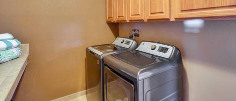 A laundry room with two washing machines, wooden cabinets, and a tiled floor.