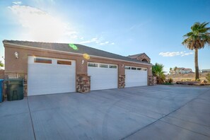 A two-story house with a garage, stone pillars, and a palm tree in the yard. - Bullhead City Vacation Rental: Private Pool & Spa! (Bullhead City)