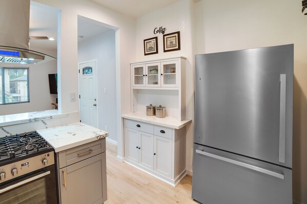 A kitchen with a stainless steel refrigerator, a stove, and a white cabinet with glass doors. - Pet-friendly Riverside Vacation Rental w/ Patio! (Riverside)
