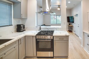 A modern kitchen with a central island, stainless steel appliances, and a large window providing natural light.