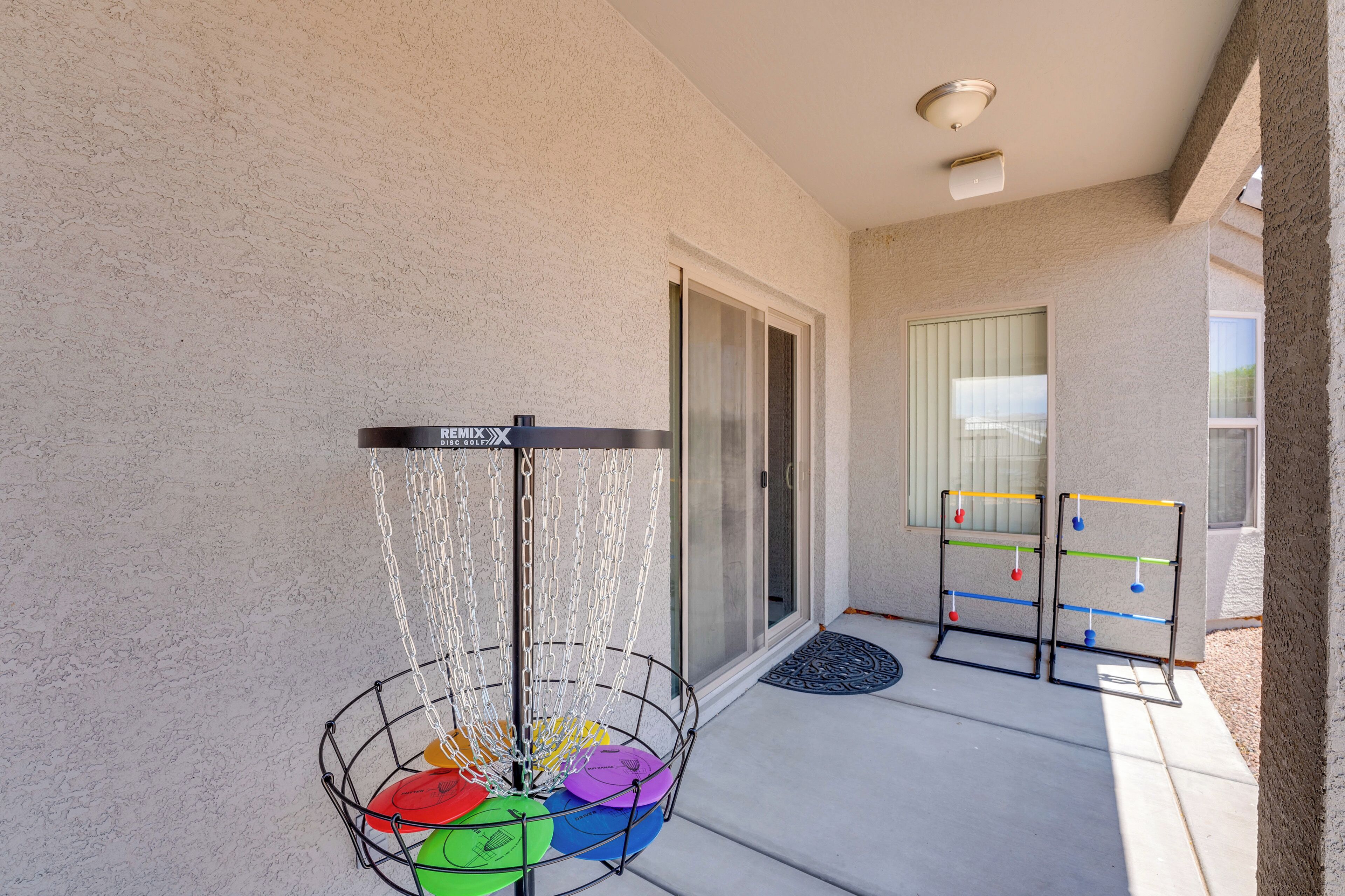 Eine Terrassenfläche mit einem Disc Golf Korb, einer Kinderspielanlage und einer Schiebetür.