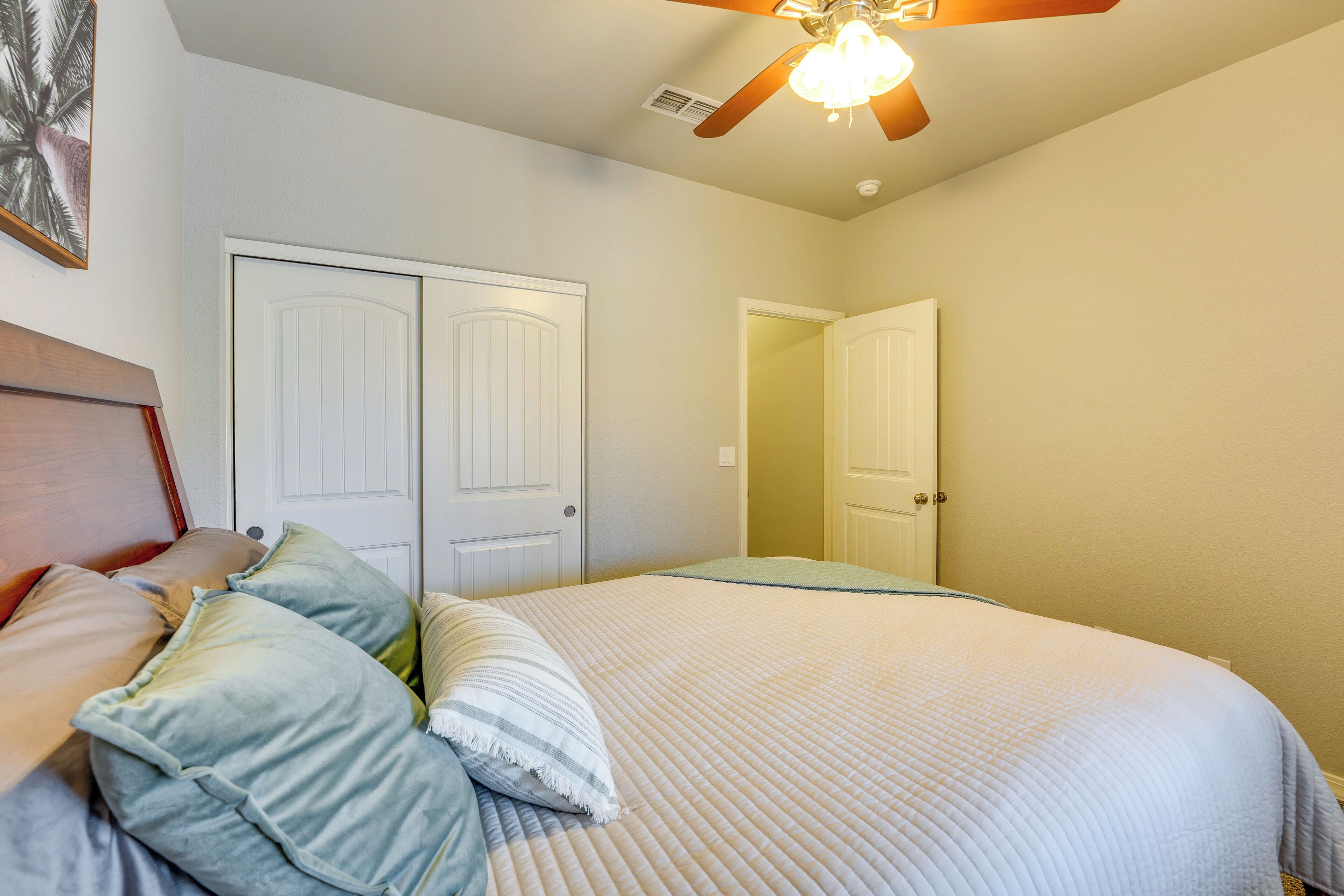 Un dormitorio con cama, dos puertas y un ventilador de techo.