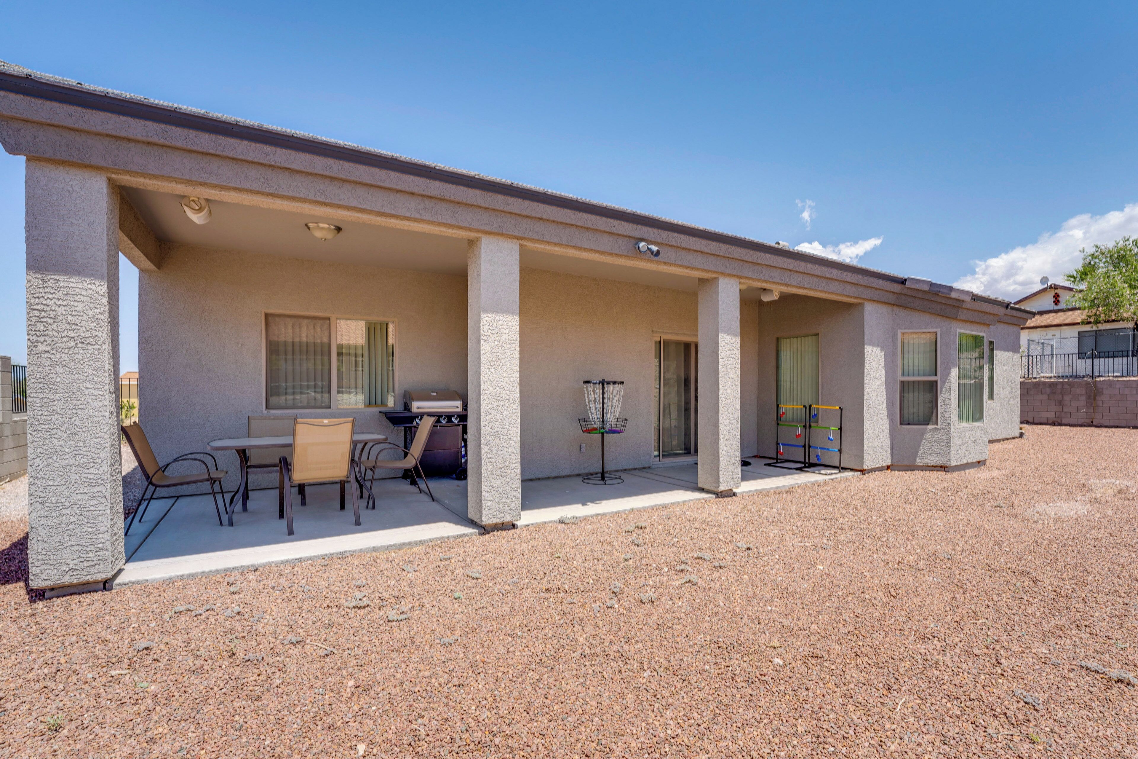 A motel with a covered patio area featuring a table and chairs, a grill, and a small basketball hoop.