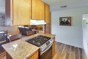 Una cocina con armarios de madera, encimera de granito, estufa y refrigerador.