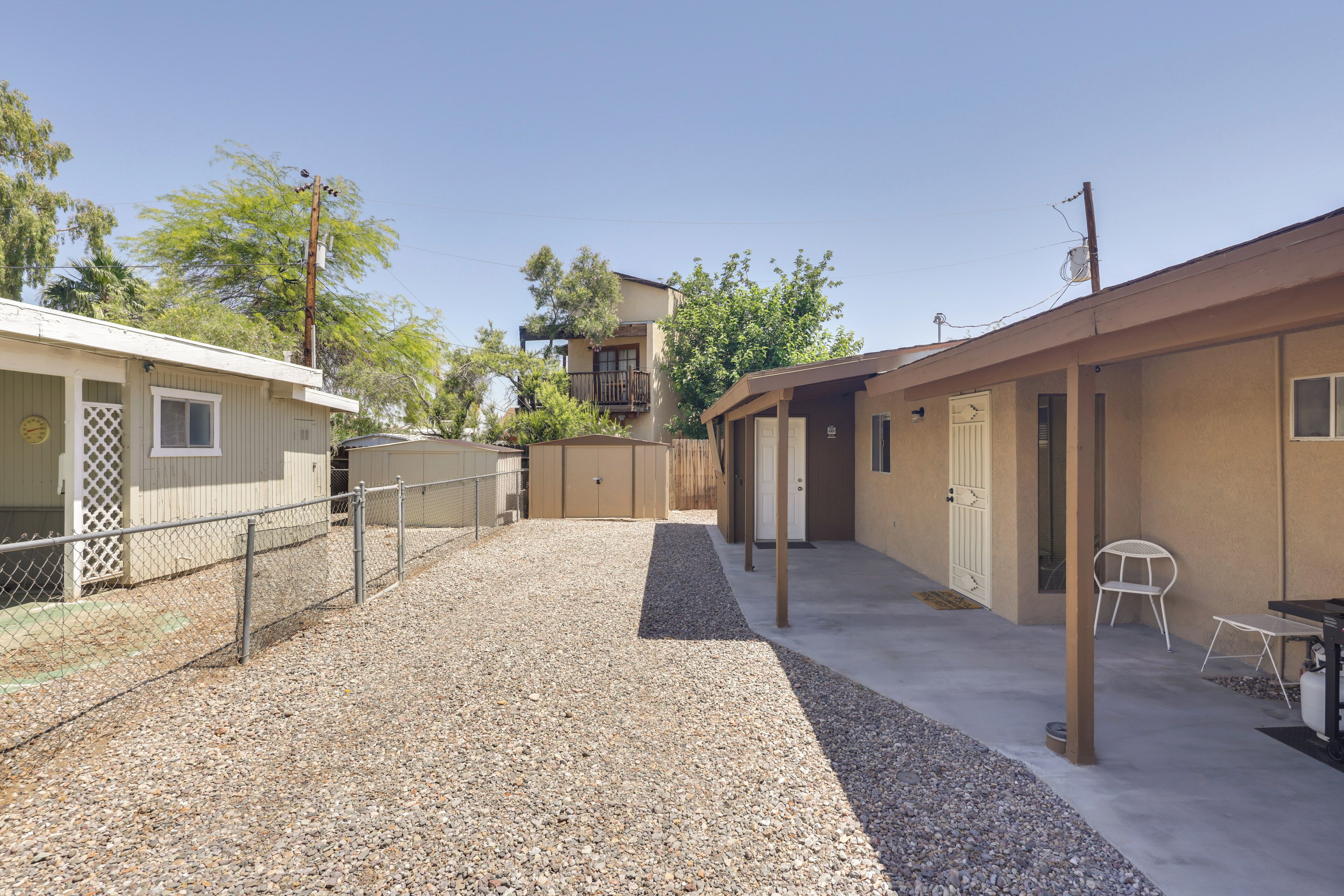 A building with a gravel courtyard, a fenced area, and a white chair.