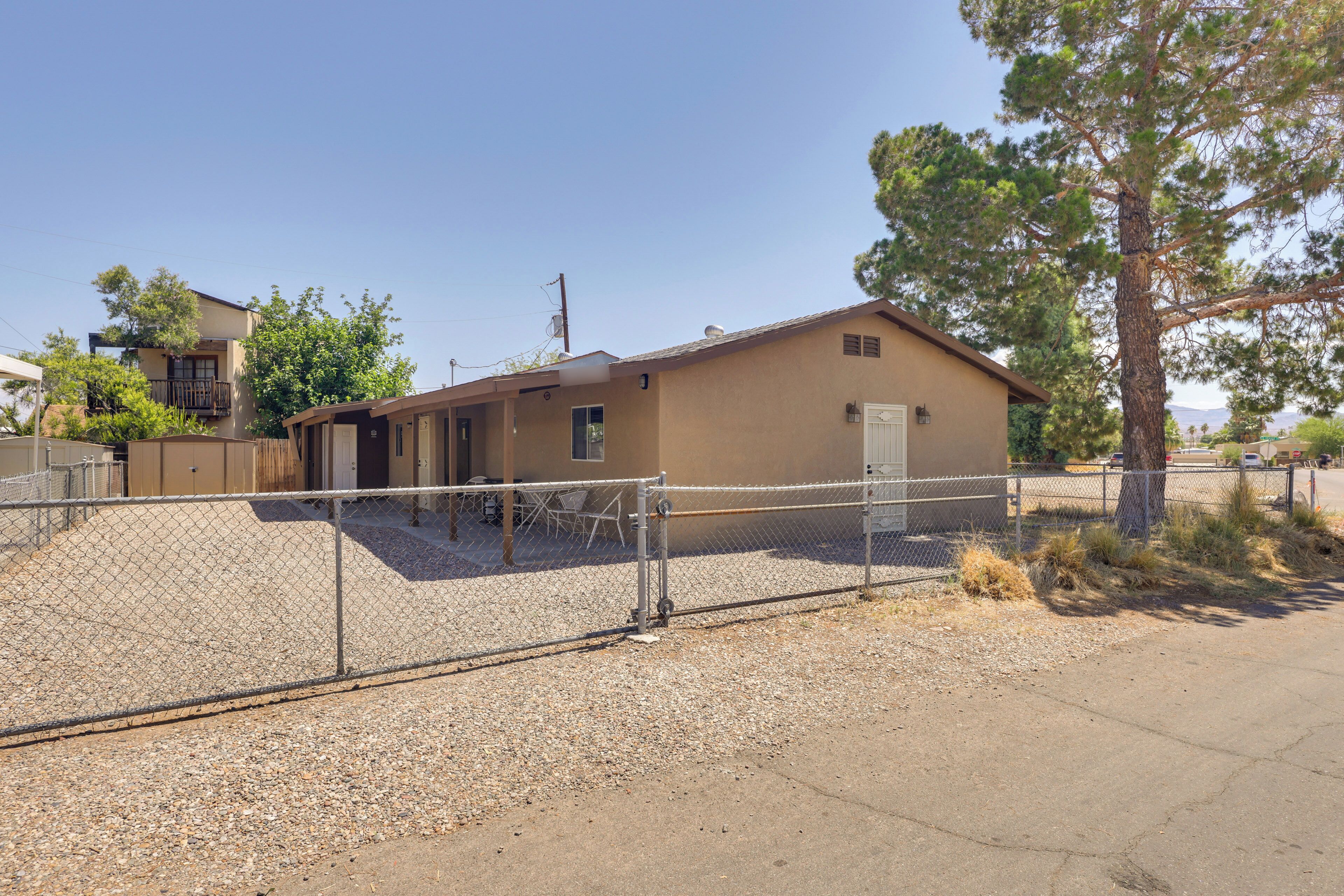 A single-story building with a fenced yard, a door, and a small porch area.