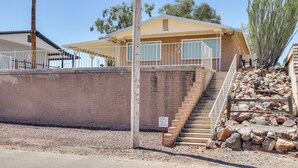 A building with a brick exterior, a wooden staircase leading to a covered area, and a sign indicating a parking area. - Riverfront Bullhead City Home w/ Mountain Views! (Bullhead City)