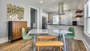 Une cuisine moderne avec un îlot central blanc, des chaises vertes et un meuble en bois.