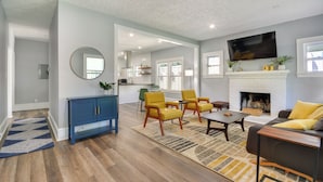 Un salon spacieux avec une cheminée, des fauteuils jaunes et un buffet bleu.