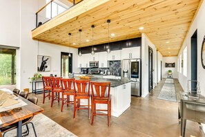 A modern kitchen with a wooden ceiling, white cabinets, and a central island with seating. - Colorado Retreat w/ Gas Grill & Mountain Views! (Fairplay)