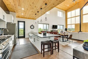 A modern kitchen with a large island, wooden ceiling, and large windows. - Colorado Retreat w/ Gas Grill & Mountain Views! (Fairplay)