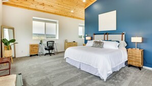 A bedroom with a large bed, a desk, and a chair. There is a window with a view of the outdoors. - Colorado Retreat w/ Gas Grill & Mountain Views! (Fairplay)