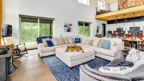 A spacious living area with a large sectional sofa, a fireplace, and a dining area with a high ceiling and large windows. - Colorado Retreat w/ Gas Grill & Mountain Views! (Fairplay)