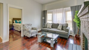 Un salon avec un canapé gris, un fauteuil à motifs et une table basse en verre.