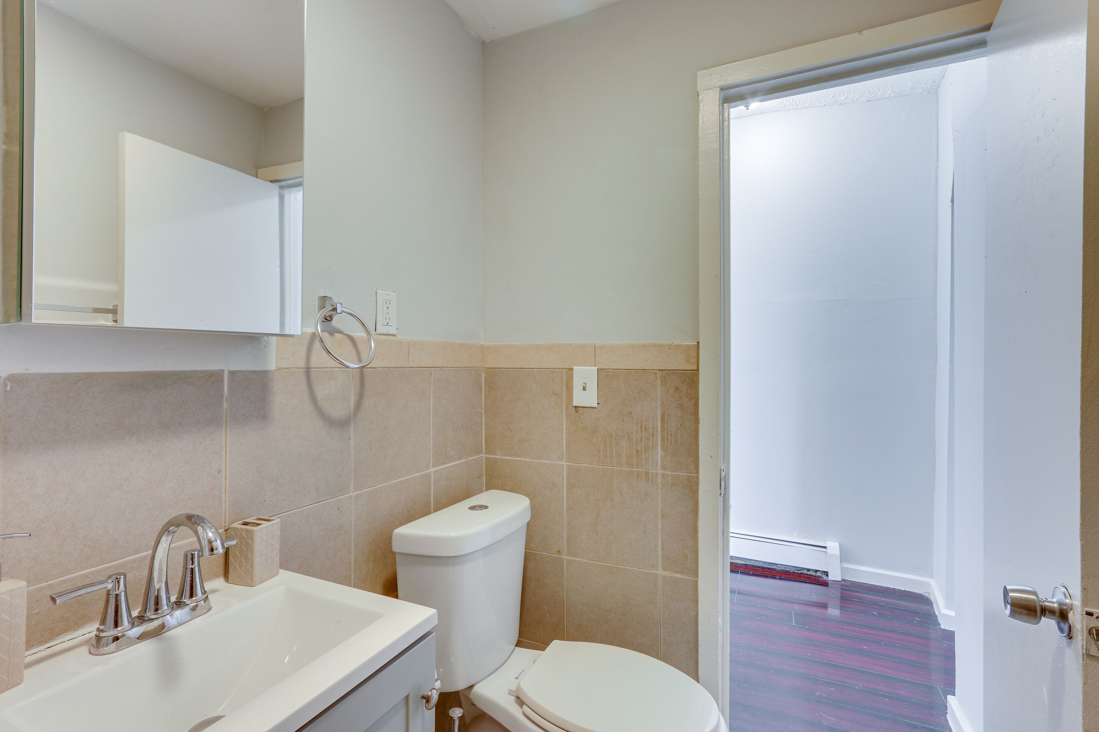 A bathroom with a white sink, a toilet, and a mirror.