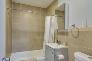 A bathroom with a bathtub, a toilet, a sink, a mirror, and a towel rack.