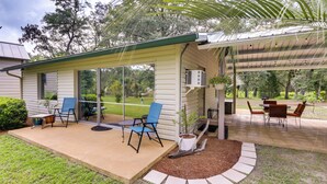 A covered patio with outdoor seating, a small table, and a potted plant. - Riverfront Florida Escape w/ Grill & Fire Pit! (Tallahassee)