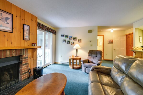 A living room with a fireplace, leather sofa, and a lamp. - Well-appointed Lincoln Abode: Ski, Swim + Fish! (Lincoln)