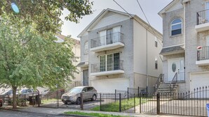 Un immeuble résidentiel de deux étages, avec une façade en briques, une entrée principale et un portail de garage visible.